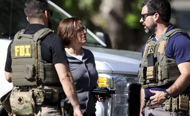 Members of FBI talk with each other at the scene of a shooting on Galway Drive in Charlotte, N.C., on Monday, April 29, 2024, Multiple law enforcement officers were shot while serving a warrant for a felon wanted for possessing a firearm. (Khadejeh Nikouyeh/The Charlotte Observer via AP)