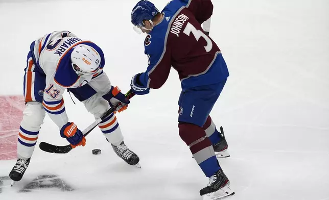 Edmonton Oilers center Mattias Janmark, left, and Colorado Avalanche defenseman Jack Johnson go after the puck during the first period of an NHL hockey game Thursday, April 18, 2024, in Denver. (AP Photo/David Zalubowski)