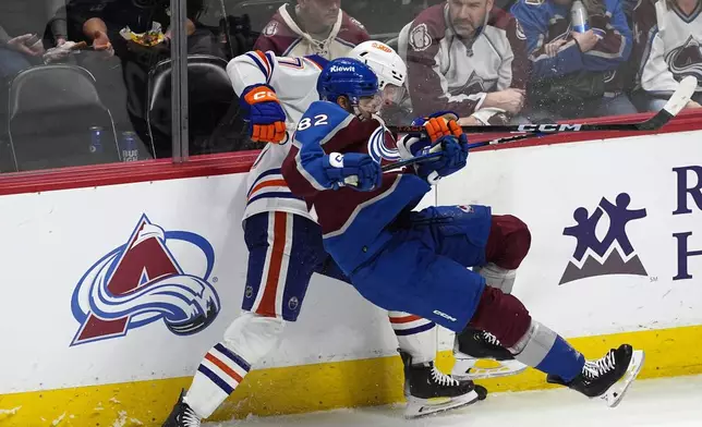 Colorado Avalanche defenseman Caleb Jones, front, falls while working for control of the puck against Edmonton Oilers defenseman Brett Kulak during the third period of an NHL hockey game Thursday, April 18, 2024, in Denver. (AP Photo/David Zalubowski)