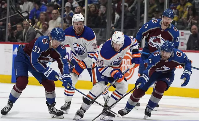Edmonton Oilers right wing Connor Brown, front center, and Colorado Avalanche center Casey Mittelstadt, left, and defenseman Devon Toews vie for the puck during the second period of an NHL hockey game Thursday, April 18, 2024, in Denver. Edmonton center Sam Carrick, back left, and Colorado right wing Valeri Nichushkin trail the play. (AP Photo/David Zalubowski)