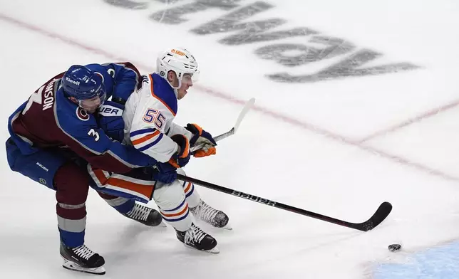 Colorado Avalanche defenseman Jack Johnson, left, wraps up Edmonton Oilers left wing Dylan Holloway during the third period of an NHL hockey game Thursday, April 18, 2024, in Denver. (AP Photo/David Zalubowski)