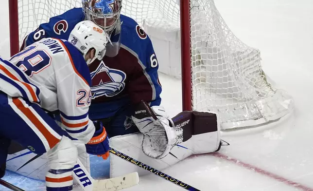 Edmonton Oilers right wing Connor Brown, front, looks to shoot against Colorado Avalanche goaltender Justus Annunen during the third period of an NHL hockey game Thursday, April 18, 2024, in Denver. (AP Photo/David Zalubowski)