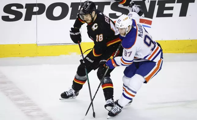 Edmonton Oilers forward Connor McDavid (97) steals the puck from Calgary Flames forward A.J. Greer (18) during the first period of an NHL hockey game Saturday, April 6, 2024, in Calgary, Alberta. (Jeff McIntosh/The Canadian Press via AP)