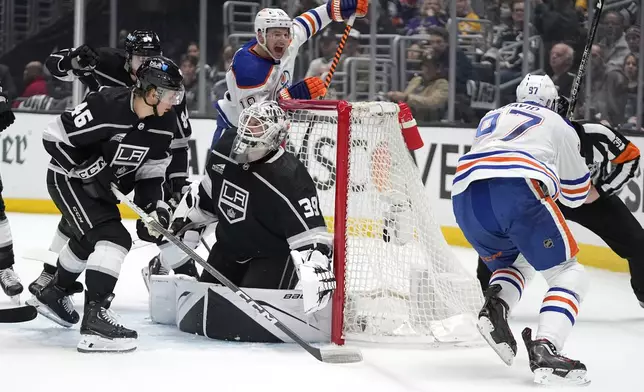Edmonton Oilers center Connor McDavid, right, celebrates his goal with left wing Zach Hyman, second from right, as Los Angeles Kings goaltender Cam Talbot, center, kneels in goal while defenseman Vladislav Gavrikov, left, and center Blake Lizotte watch during Game 3 of an NHL hockey Stanley Cup first-round playoff series Friday, April 26, 2024, in Los Angeles. (AP Photo/Mark J. Terrill)