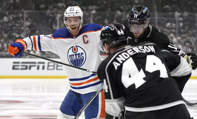 Edmonton Oilers center Connor McDavid, left, battles with Los Angeles Kings center Anze Kopitar, right, and defenseman Mikey Anderson during the third period in Game 4 of an NHL hockey Stanley Cup first-round playoff series Sunday, April 28, 2024, in Los Angeles. (AP Photo/Mark J. Terrill)
