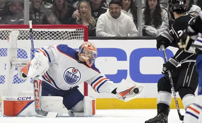 Edmonton Oilers goaltender Stuart Skinner, left, makes a glove save as Los Angeles Kings center Phillip Danault watches during the first period in Game 4 of an NHL hockey Stanley Cup first-round playoff series Sunday, April 28, 2024, in Los Angeles. (AP Photo/Mark J. Terrill)