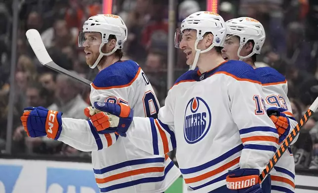Edmonton Oilers left wing Zach Hyman, center, celebrates his goal with center Connor McDavid, left, and center Ryan Nugent-Hopkins during the third period in Game 3 of an NHL hockey Stanley Cup first-round playoff series against the Los Angeles Kings Friday, April 26, 2024, in Los Angeles. (AP Photo/Mark J. Terrill)