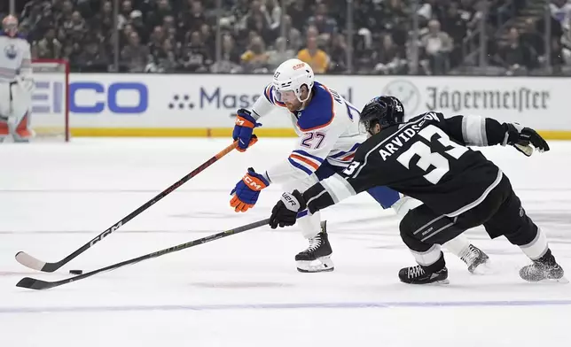 Edmonton Oilers defenseman Brett Kulak, left, reaches for the puck along with Los Angeles Kings right wing Viktor Arvidsson during Game 3 of an NHL hockey Stanley Cup first-round playoff series Friday, April 26, 2024, in Los Angeles. (AP Photo/Mark J. Terrill)