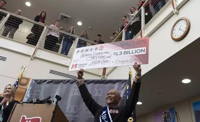 Cheng "Charlie" Saephan holds display check above his head after speaking during a news conference where it was revealed that he was one of the winners of the $1.3 billion Powerball jackpot at the Oregon Lottery headquarters on Monday, April 29, 2024, in Salem, Ore. (AP Photo/Jenny Kane)