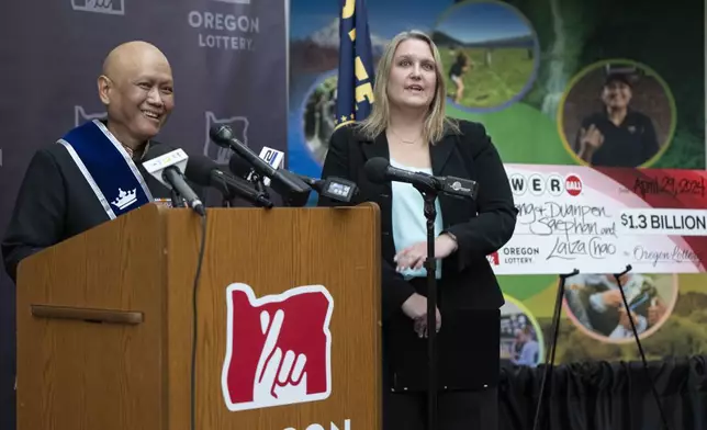 Cheng "Charlie" Saephan laughs while speaking during a press conference after it was revealed that he was one of the winners of the $1.3 billion Powerball jackpot at the Oregon Lottery headquarters on Monday, April 29, 2024, in Salem, Ore. Oregon Lottery External Communications Program Manager Melanie Mesaros listens at right. (AP Photo/Jenny Kane)