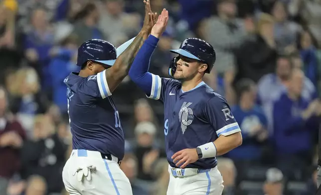 Kansas City Royals' Nelson Velazquez, left, and Michael Massey celebrate after scoring on a double hit by Hunter Renfroe during the sixth inning of a baseball game against the Baltimore Orioles Friday, April 19, 2024, in Kansas City, Mo. (AP Photo/Charlie Riedel)
