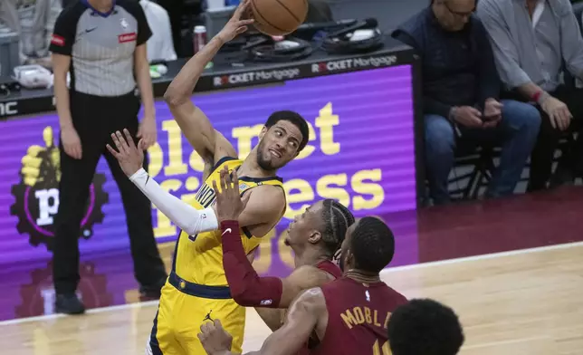 Indiana Pacers' Tyrese Haliburton, front left, looks to pass the ball as Cleveland Cavaliers' Caris LeVert, third from right, and Evan Mobley (4) defend during the first half of an NBA basketball game in Cleveland, Friday, April 12, 2024. (AP Photo/Phil Long)