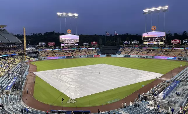 A tarp covers the field during a rain delay before a baseball game between the Los Angeles Dodgers and the San Diego Padres, Saturday, April 13, 2024, in Los Angeles. (AP Photo/Marcio Jose Sanchez)