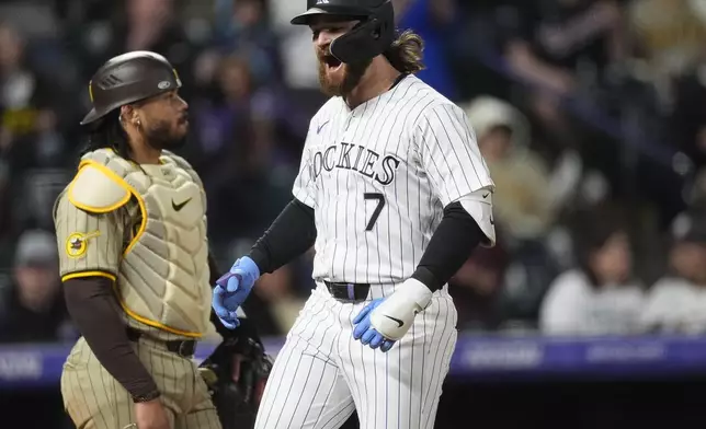 Colorado Rockies' Brendan Rodgers crosses home plate after hitting a grand slam, next to San Diego Padres catcher Luis Campusano during the fourth inning of a baseball game Tuesday, April 23, 2024, in Denver. (AP Photo/David Zalubowski)