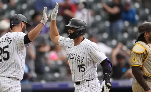 Colorado Rockies' Jacob Stallings, left, congratulates Hunter Goodman, who returns to the dugout after hitting a three-run home run off San Diego Padres relief pitcher Wandy Peralta during the eighth inning of a baseball game Thursday, April 25, 2024, in Denver. (AP Photo/David Zalubowski)