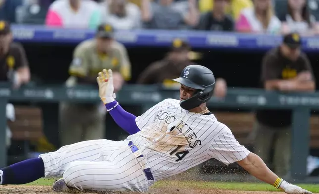 Colorado Rockies' Ezequiel Tovar scores the tying run on a wild pitch thrown by San Diego Padres' Wandy Peralta during the eighth inning of a baseball game Thursday, April 25, 2024, in Denver. (AP Photo/David Zalubowski)