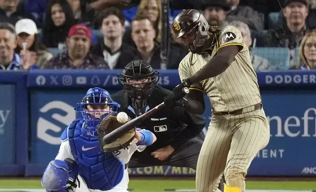 San Diego Padres' Fernando Tatis Jr., right, hits a two-run home run as Los Angeles Dodgers catcher Will Smith, left, and home plate Ryan Additon watch during the seventh inning of a baseball game April 12, 2024, in Los Angeles. Tatis Jr. plans to unveil 50 pairs of custom cleats this season.(AP Photo/Mark J. Terrill, File)