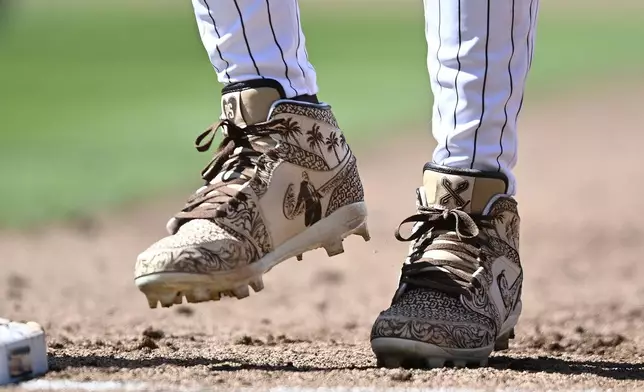 FILE - San Diego Padres' outfielder Fernando Tatis Jr. (23) wears cleats in memory of former San Diego Padres owner Peter Seidler during an Opening Day baseball game between the San Francisco Giants and the San Diego Padres, Thursday, March 28, 2024, in San Diego. Tatis plans to unveil 50 pairs of custom cleats this season in conjunction with his branding company, Xample, and Los Angeles-based Shoe Surgeon. The cleats will honor people, events and whatever strikes the 25-year-old Tatis' fancy. (AP Photo/Denis Poroy, File)