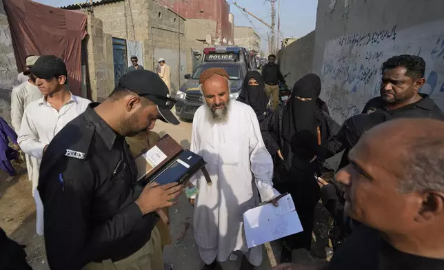 FILE - A police officer checks the document of a resident during a search operation against illegal immigrants at a neighborhood of Karachi, Pakistan, Friday, Nov. 3, 2023. For more than 1 million Afghans who fled war and poverty to Pakistan, these are uncertain times. Since Pakistan announced a crackdown on migrants last year, some 600,000 have been deported and at least a million remain in Pakistan in hiding. They've retreated from public view, abandoning their jobs and rarely leaving their neighborhoods out of fear they could be next. It's harder for them to earn money, rent accommodation, buy food or get medical help because they run the risk of getting caught by police or being reported to authorities by Pakistanis. (AP Photo/Fareed Khan, File)