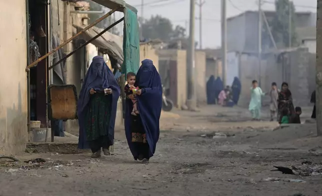 Burqa-clad Afghan women walk on a street in a a neighbourhood, where mostly Afghan populations, in Karachi, Pakistan, Friday, Jan. 26, 2024. For more than 1 million Afghans who fled war and poverty to Pakistan, these are uncertain times. Since Pakistan announced a crackdown on migrants last year, some 600,000 have been deported and at least a million remain in Pakistan in hiding. They've retreated from public view, abandoning their jobs and rarely leaving their neighborhoods out of fear they could be next. It's harder for them to earn money, rent accommodation, buy food or get medical help because they run the risk of getting caught by police or being reported to authorities by Pakistanis. (AP Photo/Fareed Khan)
