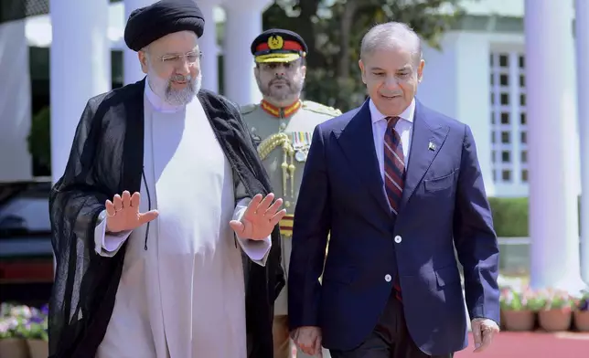 In this photo released by Prime Minister Office, Iranian President Ebrahim Raisi, left, walks with Pakistan's Prime Minister Shehbaz Sharif during a welcome ceremony in the prime minister house in Islamabad, Pakistan, Monday, April 22, 2024. (Prime Minister Office via AP)