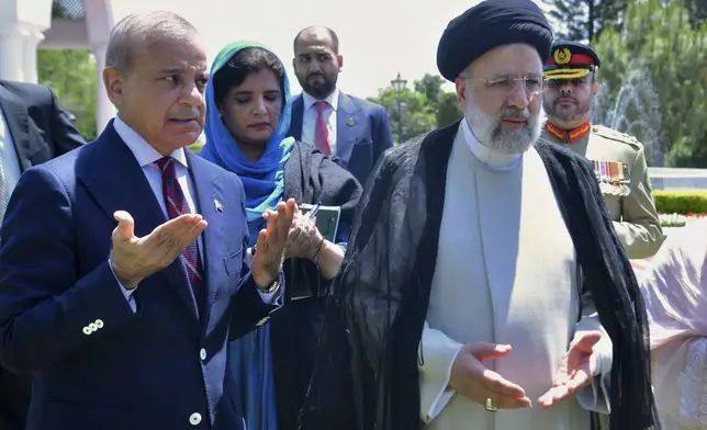 In this photo released by Prime Minister Office, Iranian President Ebrahim Raisi, right, with Pakistan's Prime Minister Shehbaz Sharif, left, prays after planting a tree in the prime minister house in Islamabad, Pakistan, Monday, April 22, 2024. (Prime Minister Office via AP)