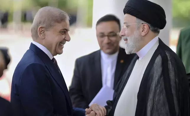 In this photo released by Prime Minister Office, Pakistan's Prime Minister Shehbaz Sharif, left, greets to Iranian President Ebrahim Raisi upon his arrival in the prime minister house in Islamabad, Pakistan, Monday, April 22, 2024. (Prime Minister Office via AP)
