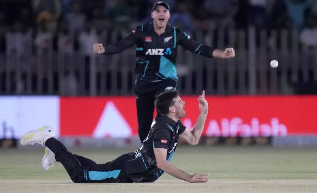 New Zealand's Ben Lester, bottom, reacts after taking the catch of Pakistan's Saim Ayub during the second T20 international cricket match between Pakistan and New Zealand, in Rawalpindi, Pakistan, Saturday, April 20, 2024. (AP Photo/Anjum Naveed)