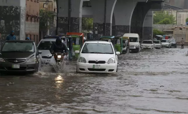 A motorcyclist and car drivers drive through a flooded road caused by heavy rain in Peshawar, Pakistan, Monday, April 15, 2024. Lightening and heavy rains killed dozens of people, mostly farmers, across Pakistan in the past three days, officials said Monday, as authorities declared a state of emergency in the country's southwest following an overnight rainfall to avoid any further casualties and damages. (AP Photo/Muhammad Sajjad)