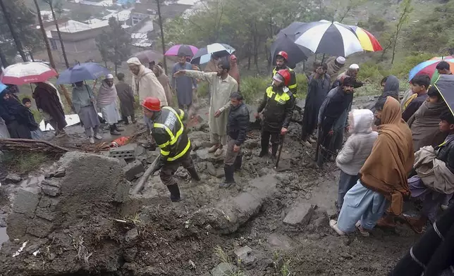 In this photo provided by the Rescue 1122 Emergency Department, rescue workers and locals gather to clear the rubble of a house partially damaged by landslide due to heavy rainfall in Matta, a town in Swat Valley, Pakistan, Sunday, April 14, 2024. Lightening and heavy rains killed dozens of people, mostly farmers, across Pakistan in the past three days, officials said Monday, as authorities declared a state of emergency in the country's southwest following an overnight rainfall to avoid any further casualties and damages. (Rescue 1122 Emergency Department via AP)