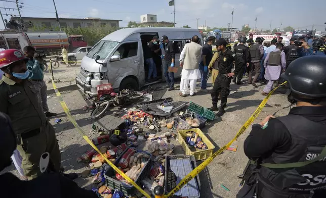 Pakistani investigators examine a damaged van at the site of a suicide attack in Karachi, Pakistan, Friday, April 19, 2024. A suicide bomber detonated his explosive-laden vest near a van carrying Japanese autoworkers, who narrowly escaped the attack Friday that wounded three bystanders in Pakistan's port city of Karachi, police said. (AP Photo/Fareed Khan)