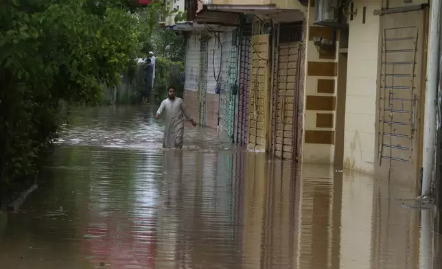 A Pakistani wades through a flooded street caused by heavy rain in Peshawar, Pakistan, Monday, April 15, 2024. Lightening and heavy rains killed dozens of people, mostly farmers, across Pakistan in the past three days, officials said Monday, as authorities declared a state of emergency in the country's southwest following an overnight rainfall to avoid any further casualties and damages. (AP Photo/Muhammad Sajjad)