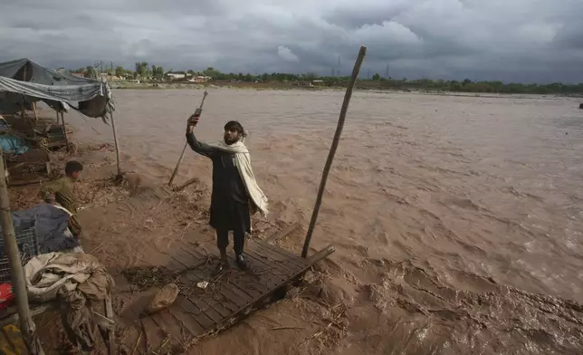 A man takes a selfie on the bank of a stream, which is overflowing following heavy rains, on the outskirts of Peshawar, Pakistan, Monday, April 15, 2024. Lightnings and heavy rains killed dozens of people, mostly farmers, across Pakistan in the past three days, officials said Monday, as authorities declared a state of emergency in the country's southwest following an overnight rainfall to avoid any further casualties and damages. (AP Photo/Muhammad Sajjad)