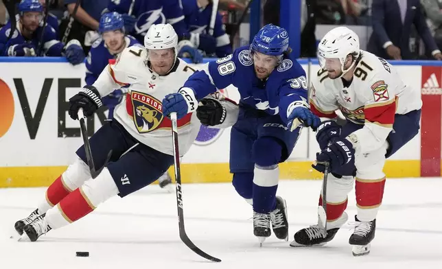 Tampa Bay Lightning left wing Brandon Hagel (38) gets sandwiched by Florida Panthers defenseman Dmitry Kulikov (7) and defenseman Oliver Ekman-Larsson (91) during the second period in Game 4 of an NHL hockey Stanley Cup first-round playoff series, Saturday, April 27, 2024, in Tampa, Fla. (AP Photo/Chris O'Meara)