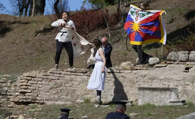 FILE - Police officers run to detain protesters displaying a Tibetan flag and a banner disrupting the lighting of the Olympic flame at Ancient Olympia site, birthplace of the ancient Olympics in southwestern Greece, Oct. 18, 2021. On Tuesday, April 16, 2024 the flame for this summer's Paris Olympics will be lit and be carried through Greece for more than 5,000 kilometers (3,100 miles) before being handed over to French organizers at the Athens site of the first modern Olympics. (AP Photo/Thanassis Stavrakis, File)
