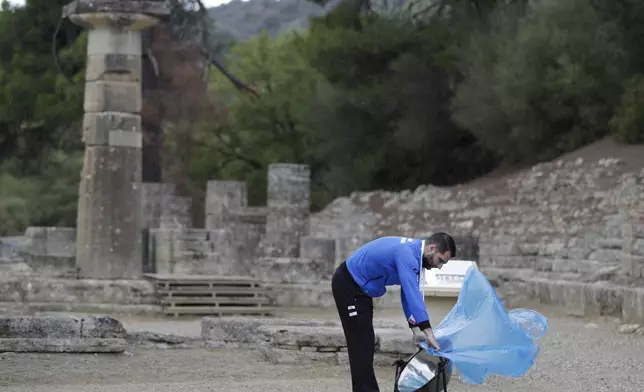 FILE - An official places a cover over the cauldron to protect it from rain before the lighting ceremony of the Olympic flame in Ancient Olympia, southwestern Greece, Oct. 24, 2017. On Tuesday, April 16, 2024 the flame for this summer's Paris Olympics will be lit and be carried through Greece for more than 5,000 kilometers (3,100 miles) before being handed over to French organizers at the Athens site of the first modern Olympics. (AP Photo/Thanassis Stavrakis, File)