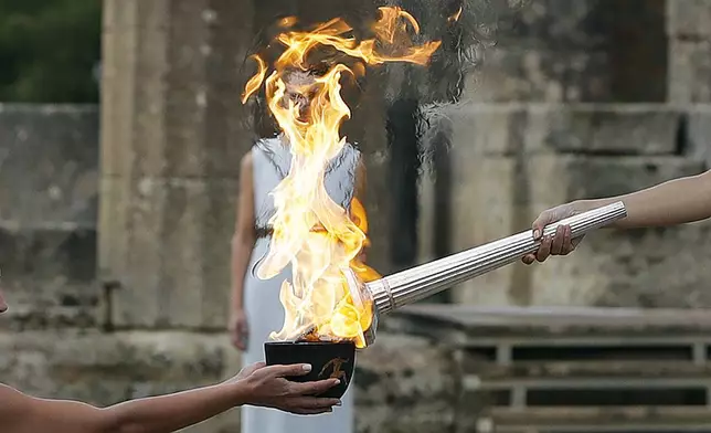 FILE - Actress Katerina Lehou, right, as high priestess, lights the torch during the lighting ceremony of the Olympic flame in Ancient Olympia, southwestern Greece, Oct. 24, 2017. On Tuesday, April 16, 2024 the flame for this summer's Paris Olympics will be lit and be carried through Greece for more than 5,000 kilometers (3,100 miles) before being handed over to French organizers at the Athens site of the first modern Olympics. (AP Photo/Thanassis Stavrakis, File)