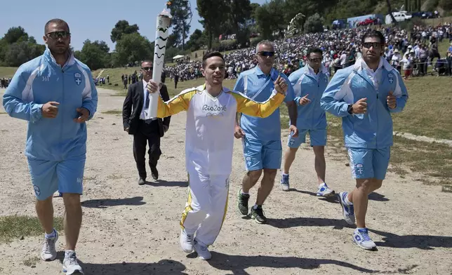 FILE -The first torch bearer, Greek gymnast Eleftherios Petrounias runs with the torch after the ceremonial lighting of the Olympic flame in Ancient Olympia, Greece, on April 21, 2016. On Tuesday, April 16, 2024 the flame for this summer's Paris Olympics will be lit and be carried through Greece for more than 5,000 kilometers (3,100 miles) before being handed over to French organizers at the Athens site of the first modern Olympics. (AP Photo/Petros Giannakouris, File)