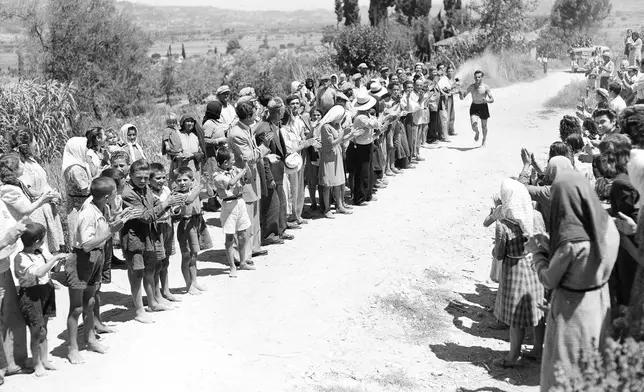 FILE - Villagers in Strefi, Greece, cheer a runner carrying the Olympic flame in the relay from Olympia to Pyrgos, July 20, 1948. On Tuesday, April 16, 2024 the flame for this summer's Paris Olympics will be lit and be carried through Greece for more than 5,000 kilometers (3,100 miles) before being handed over to French organizers at the Athens site of the first modern Olympics. (AP Photo, File)