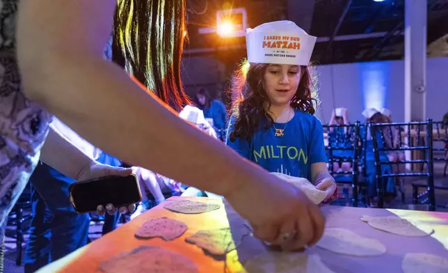 Charlotte Gleicher, 7, a first grader at Milton Gottesman Jewish Day School of the Nation's Capital, brings up dough to be baked into matzah that she made during a "Matzah Factory" event at the JCrafts Center for Jewish Life and Tradition in Rockville, Md., Thursday, April 18, 2024, ahead of the Passover holiday which begins next Monday evening. To be kosher for Passover, which begins next Monday evening, the dough has to be prepared and cooked all within 18 minutes and not allowed to rise. (AP Photo/Jacquelyn Martin)