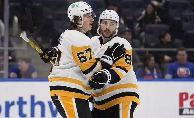 Pittsburgh Penguins' Rickard Rakell, left, celebrates his goal against the New York Islanders with Michael Bunting during the first period of an NHL hockey game Wednesday, April 17, 2024, in Elmont, N.Y. (AP Photo/Seth Wenig)