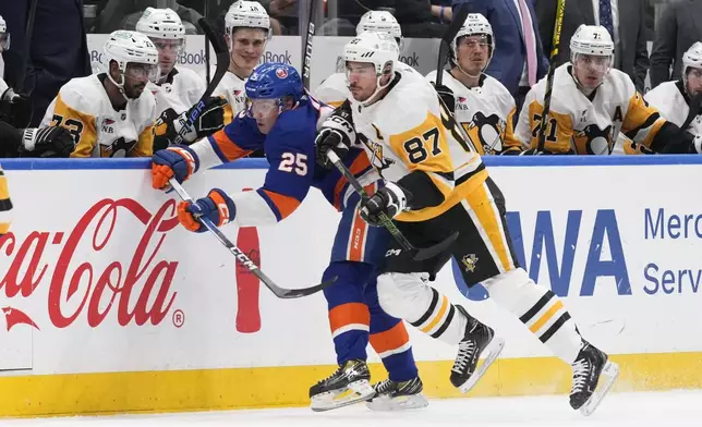 Pittsburgh Penguins' Sidney Crosby (87) lays a hit on New York Islanders' Sebastian Aho during the second period of an NHL hockey game Wednesday, April 17, 2024, in Elmont, N.Y. (AP Photo/Seth Wenig)