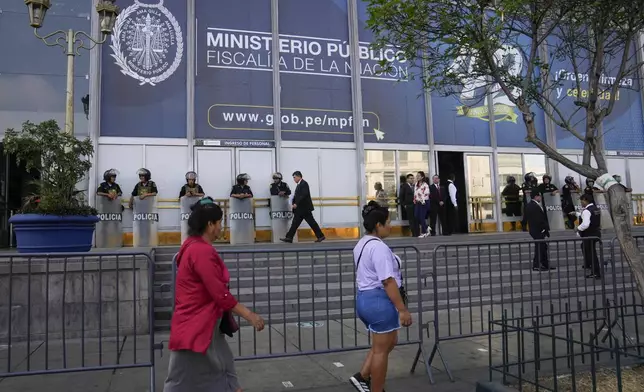 Pedestrians walk past the public prosecutor's office where Peruvian President Dina Boluarte arrived to testify, in Lima, Peru, Friday, April 5, 2024. Authorities are investigating on whether she illegally received hundreds of thousands of dollars in cash, luxury watches and jewelry. (AP Photo/Martin Mejia)