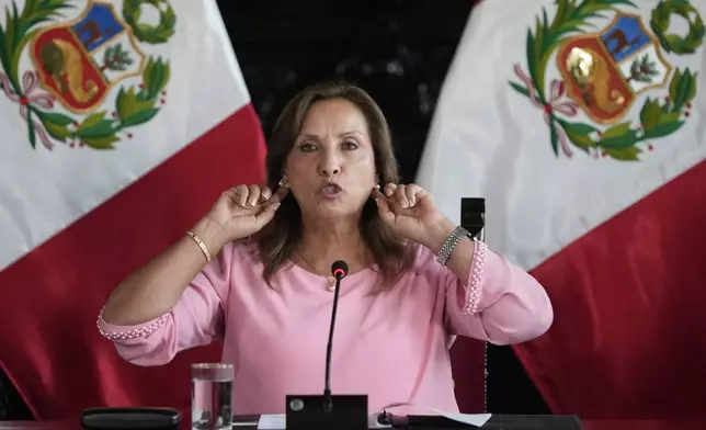 Peru's President Dina Boluarte points to the earrings she is wearing, during a press conference at Government Palace, in Lima, Peru, Friday, April 5, 2024. Authorities are investigating on whether she illegally received hundreds of thousands of dollars in cash, luxury watches and jewelry. (AP Photo/Martin Mejia)