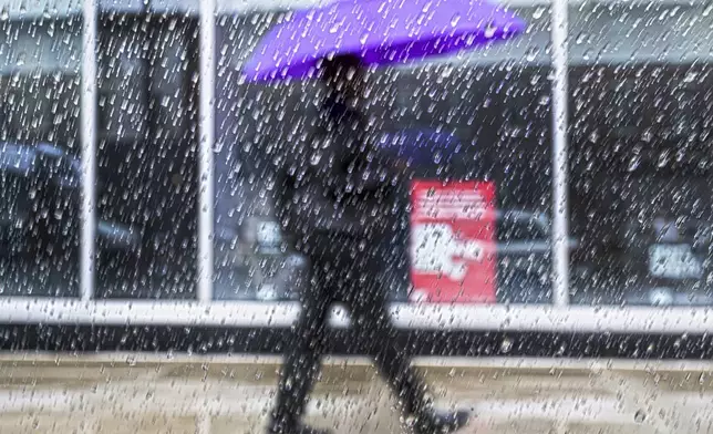 Raindrops fall on a window pane as a pedestrian walks by on Tuesday, Apr 4, 2024, during a heavy rainfall in Philadelphia. (Jose F. Moreno/The Philadelphia Inquirer via AP)