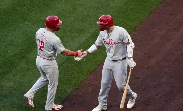 Philadelphia Phillies designated hitter Kyle Schwarber, left, celebrates with Nick Castellanos, right, after scoring off a single hit by Alec Bohm during the first inning of a baseball game against the Los Angeles Angels, Monday, April 29, 2024, in Anaheim, Calif. (AP Photo/Ryan Sun)