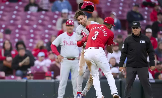 Philadelphia Phillies' Trea Turner, middle, is tagged out by Cincinnati Reds' Jeimer Candelario, right, on a steal attempt during the fifth inning of a baseball game in Cincinnati on Friday, Wednesday, April 24, 2024. (AP Photo/Aaron Doster)
