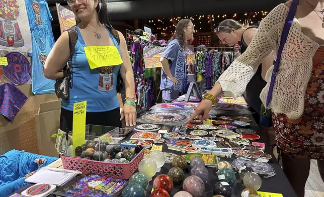 This photo shows Kim Mancini of Reading, Pa. selling Phish inspired posters and stickers during PhanArt on Saturday, April 20, 2024, at the Brooklyn Bowl in Las Vegas. (AP Photo/Josh Cornfield)