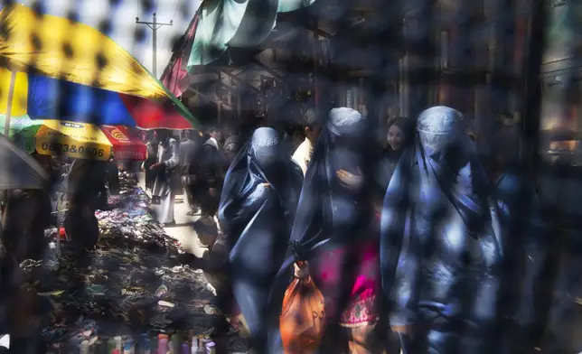 FILE - Seen through the eye grid of a burqa, women walk through a market in Kabul, Afghanistan on Thursday, April 11, 2013. (AP Photo/Anja Niedringhaus, File)