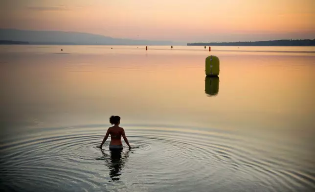 FILE - A woman takes a dip in Lake Geneva at sunrise in Geneva, Switzerland on Sunday, July 21, 2013. (AP Photo/Anja Niedringhaus, File)